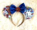 Galactic Holiday Cheer mouse ear headband with Christmas space character fabric, royal-blue velvet bow, red glitter poinsettia, white pearl trim, and ivory headband.
