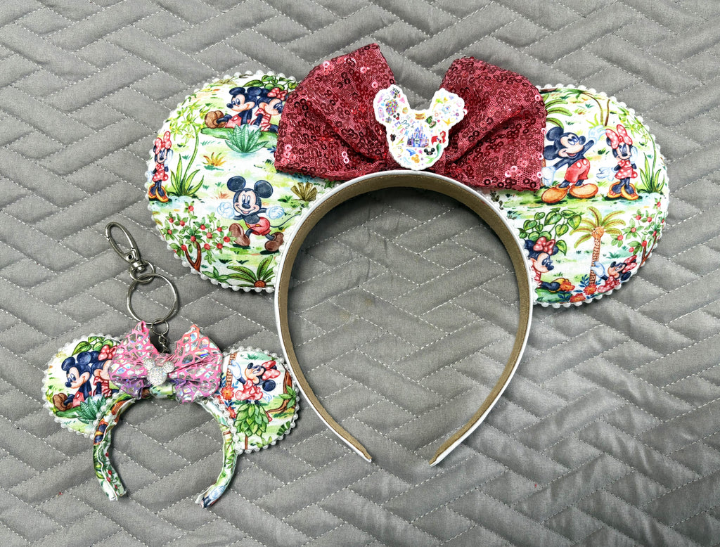 Handcrafted Picnic Pals Pixie Pair featuring a classic character-inspired mouse ear headband and coordinating Mini Magic Charm with colorful picnic artwork, tropical scenery, burgundy sequin bow, decorative pearl trim, and handcrafted boutique styling.
