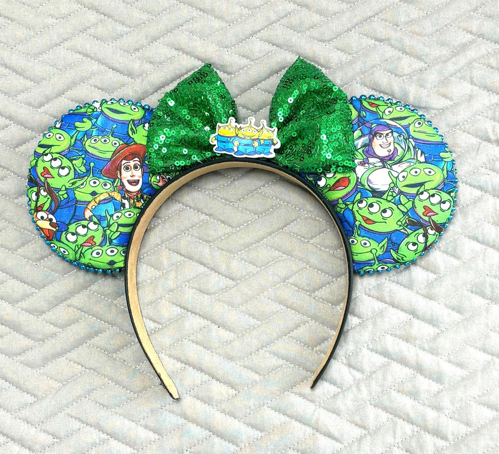 Cosmic Claw Crew Boutique Mouse Ear Headband featuring playful space-inspired artwork, an emerald green sequin bow, and handcrafted boutique styling by Pixie Park Co.