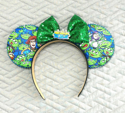 Cosmic Claw Crew Boutique Mouse Ear Headband featuring playful space-inspired artwork, an emerald green sequin bow, and handcrafted boutique styling by Pixie Park Co.